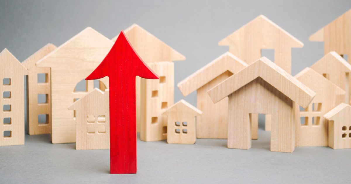 CONCEPT Red arrow up and miniature wooden houses