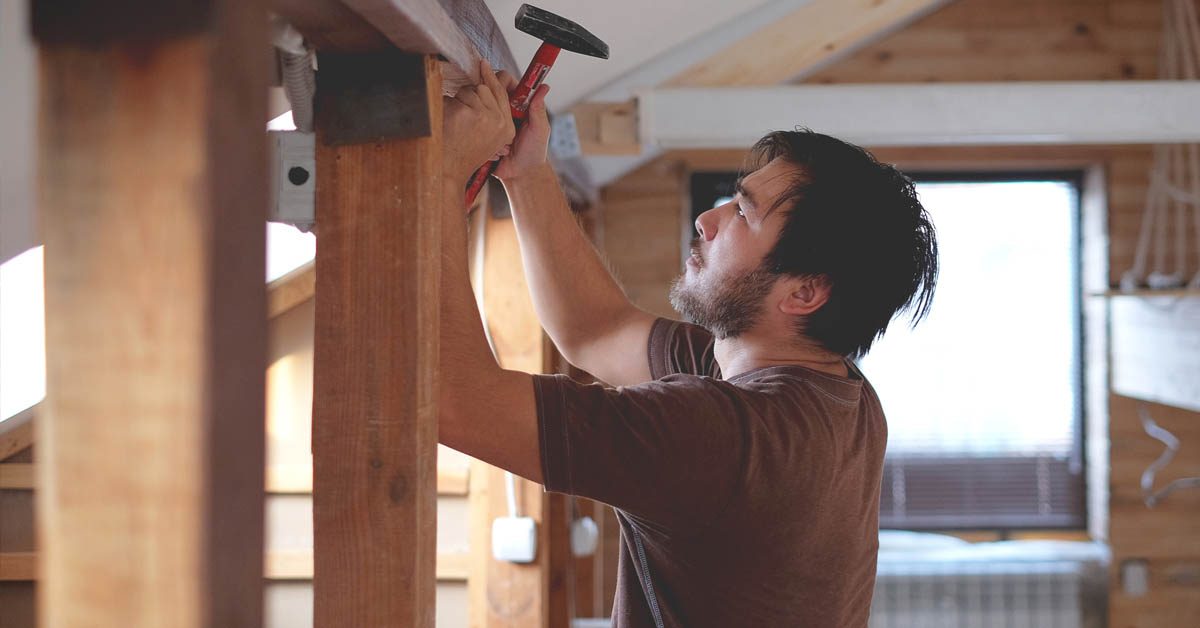 CONSTRUCTION Man building a house working with hammer