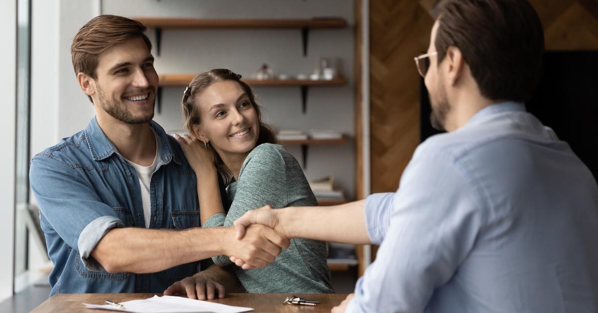 PEOPLE Happy couple shakes hand of real estate professional