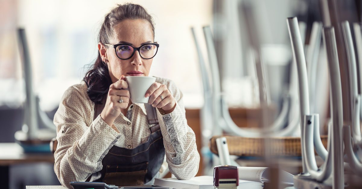 PEOPLE Restaurant owner sips coffee sitting over accounting