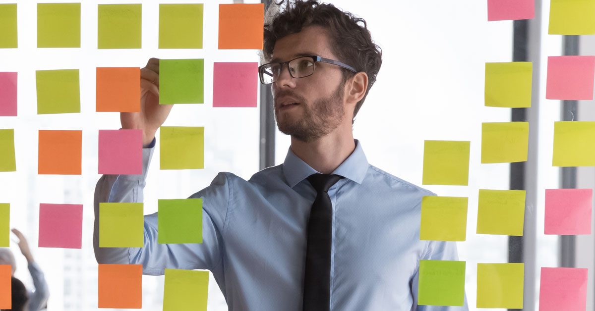 PEOPLE Young man managing project tasks on sticky notes