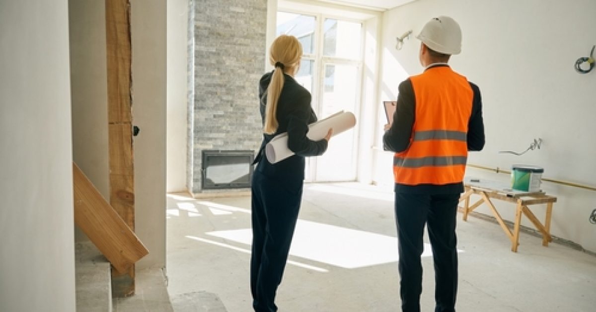 Female,Client,And,Male,Engineer,Standing,In,Room,Under,Construction