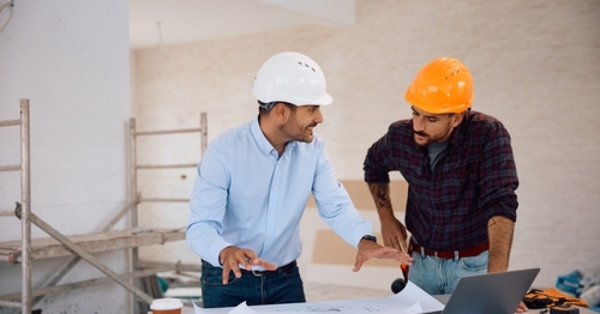 Happy,Architect,Talking,To,Construction,Worker,While,Analyzing,Blueprints,During